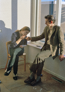 831239 Afbeelding van een man die een vrouw een vuurtje geeft om een sigaret aan te steken.